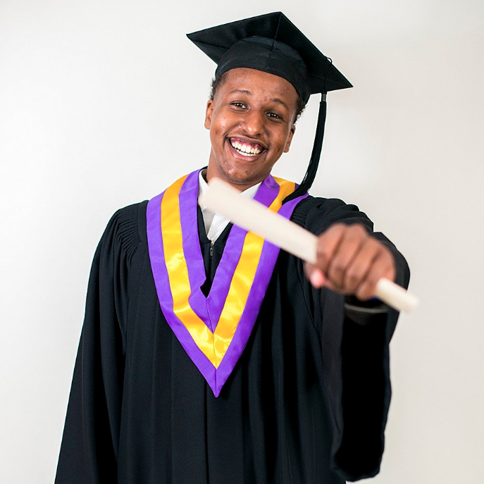Photo of graduate holding diploma out and smiling