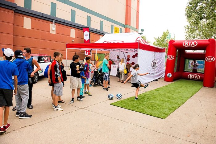 Car company tent at an outdoor sporting event with a long lineup