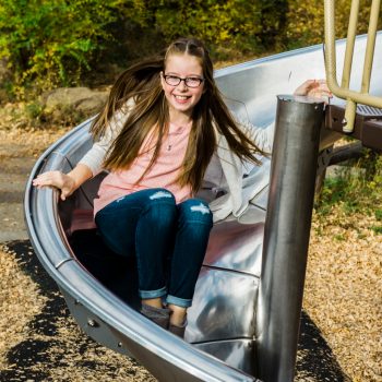 Girl smiles as she goes down a slide in Rundle Park