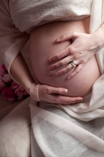 woman lovingly holding her pregnant belly