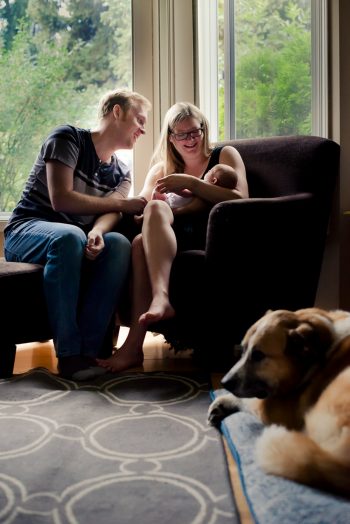 Family dog looks on while couple celebrates their new baby