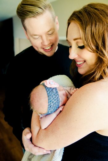 Smiling couple looks into the face of their newborn baby girl